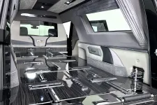 Thumbnail for Interior of a luxury black hearse with glossy wood paneling, chrome fixtures, and custom upholstery.