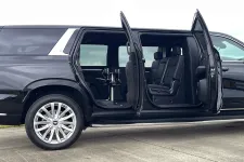 Thumbnail for Black luxury SUV with rear doors open revealing spacious leather interior and a center table inside.