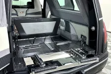 Thumbnail for Interior view of a black hearse with polished wood and leather detailing and an open rear compartment.