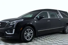 Thumbnail for Black Cadillac hearse with chrome details parked on checkered floor under white lighting.