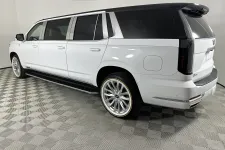 Thumbnail for White luxury extended SUV with tinted windows and chrome rims displayed in a showroom with checkered flooring.