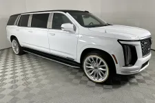 Thumbnail for White luxury extended SUV limousine with sleek design and tinted windows in showroom with patterned floor.
