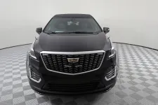 Thumbnail for Front view of a sleek black Cadillac XT5 SUV on a checkered floor background.