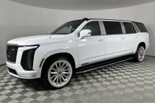 Thumbnail for White extended luxury SUV limousine with modern design, large wheels, and tinted windows parked on checkered floor.