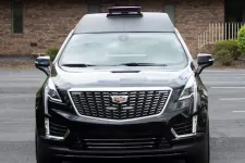 Thumbnail for Front view of a sleek black Cadillac SUV parked outside a building.