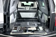 Thumbnail for Interior of a luxury hearse with polished wood, leather details, and Cadillac emblem at the front.