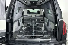 Thumbnail for Interior view of a luxury black Cadillac hearse with a polished casket platform and elegant gray upholstery.