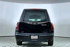 Thumbnail for Rear view of a black Cadillac hearse with tinted windows on a checkered floor in a bright showroom.