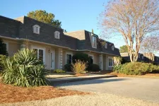Thumbnail for Row of single-story townhouses with manicured shrubs and large deciduous trees on a clear sunny day