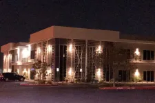 Thumbnail for Modern two-story office building lit by exterior lights at night with parked cars nearby