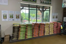 Thumbnail for Stacks of colorful Dr. Earth's organic gardening soil bags displayed indoors near large windows in a nursery.
