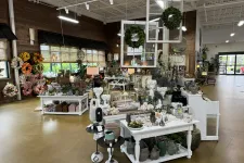 Thumbnail for Interior of a bright home decor store displaying floral wreaths, vases, sculptures, and decorative items on tables.