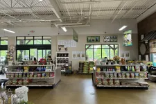Thumbnail for Interior of a bright gardening store with shelves of seeds, soil bags, gardening tools, and plants near large windows.