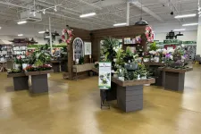 Thumbnail for Indoor garden section in a store with various potted plants and flowers displayed on wooden tables.
