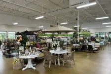 Thumbnail for Indoor garden center with patio furniture, umbrellas, plants, and garden supplies on display under bright lighting.