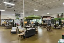 Thumbnail for Indoor garden center showroom with outdoor furniture, umbrellas, plants, and home decor displays under bright lighting.