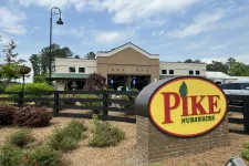 Thumbnail for Pike Nurseries sign in front of a landscaped garden and a brick building under a partly cloudy sky.