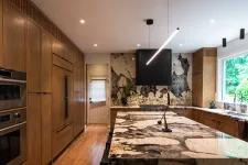Thumbnail for Modern kitchen with large patterned marble island, wooden cabinets, stainless steel appliances, and large window.
