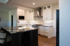 Thumbnail for Modern kitchen with white cabinets, marble island countertop, stainless steel appliances, and hardwood floors