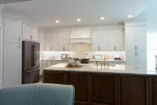 Thumbnail for Modern kitchen with white cabinets, dark wood island, marble countertop, brass faucet, and stainless steel refrigerator.