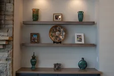 Thumbnail for Blue cabinet with decorative vases, photo frames, and illuminated shelves in a cozy stone-walled corner.