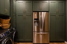 Thumbnail for Modern laundry room with olive green cabinets, stainless steel refrigerator, washer, dryer, and woven baskets.