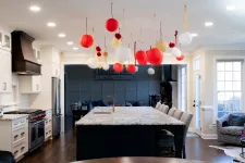 Thumbnail for Modern kitchen with marble island, white cabinetry, stainless appliances, and red and white hanging lantern decorations.
