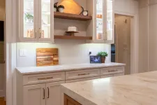Thumbnail for Modern kitchen with white cabinetry, wooden island, marble countertops, glass-front cabinets, and warm lighting.