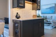 Thumbnail for Modern kitchen bar area with black cabinets, wine fridge, glass shelves, and white subway tile backsplash.