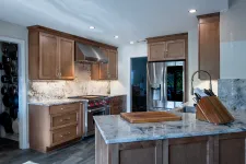 Thumbnail for Modern kitchen with wooden cabinets, granite countertops, stainless steel appliances, and a large island with cutting board.