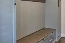 Thumbnail for Built-in gray storage bench with wooden seat and tall cabinet in a room with hardwood floor.