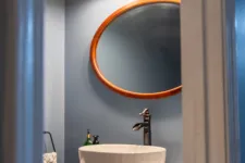 Thumbnail for Bathroom vanity with round mirror, vessel sink, bronze faucet, wooden cabinet, and Tiffany-style light fixtures.