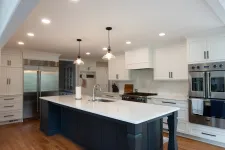 Thumbnail for Modern kitchen with white cabinets, marble countertops, large island, stainless steel appliances, and wood flooring
