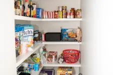 Thumbnail for Organized pantry with shelves stocked with snacks, canned goods, bottled drinks, water packs, and kitchen items.