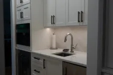 Thumbnail for Modern kitchen with white cabinets, stainless steel sink, built-in appliances, and wooden floor.