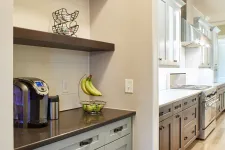 Thumbnail for Modern kitchen with gray and wood cabinets, coffee maker, fruit basket, and wooden TEA letters on shelves