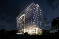 Thumbnail for Modern glass office building illuminated at night with signage and surrounding trees under a starry sky.