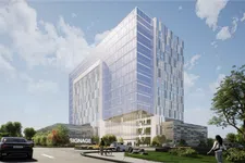 Thumbnail for Modern glass office building with reflective windows under blue sky, surrounded by greenery and cars.