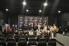Thumbnail for Group of people posing in a theater with Shrimp Tank branded backdrop and empty chairs in the foreground.