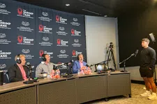 Thumbnail for Three men seated at a podcast table labeled The Shrimp Tank with a young man standing opposite, recording setup visible.