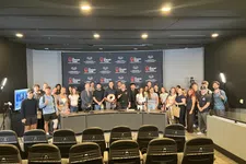Thumbnail for Group photo of diverse individuals standing in front of a Shrimp Tank event banner in a conference room.
