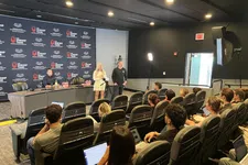 Thumbnail for Presenters speaking to an attentive audience in a conference room with The Shrimp Tank branding on backdrop.