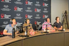 Thumbnail for Four panelists with headphones sit at a podcast table discussing with microphones and branded backdrop for The Shrimp Tank.