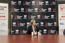 Thumbnail for a man and woman sitting at a table with microphones and a sign