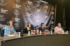 Thumbnail for Four hosts with microphones and headphones recording a podcast at The Shrimp Tank event table with branded backdrop.
