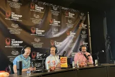 Thumbnail for a group of people sitting at a table with microphones and a large banner behind them