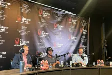 Thumbnail for Three men with headsets and microphones seated at a table with The Shrimp Tank branded backdrop during a podcast or interview.