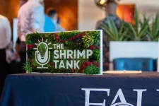 Thumbnail for Decorative sign for The Shrimp Tank event on a table with FAU branding and blurred people in the background
