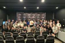 Thumbnail for Group photo of diverse young adults in a seminar room with Shrimp Tank branding backdrop and seats in front