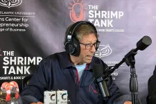 Thumbnail for Man wearing headphones speaking into a microphone at The Shrimp Tank podcast with drink cans on the table